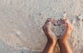 Child girl holding sand make heart shape in hands and playing on the beach Royalty Free Stock Photo