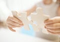 Child girl holding two big wooden puzzle pieces. Hands connecting jigsaw puzzle. Close up photo with small dof Royalty Free Stock Photo