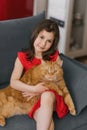 Child girl holds her pet red British cat in her arms and sits with him on the couch at home Royalty Free Stock Photo