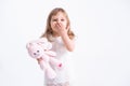 Child girl hugging her pink teddy bunny sending a kiss on white background. Cute girl with her toy