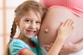 Child girl hugs belly of her pregnant mother