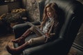 Child girl in image of Sherlock Holmes sits in armchair and reads newspaper on background of old interior. Royalty Free Stock Photo