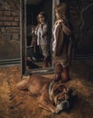 Child girl in image of Sherlock Holmes stands next to English bulldog and looks at mirror reflection on background of old interior Royalty Free Stock Photo