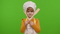 Child girl kid dressed as cook chef with fork and spatula, showing symbol of rejection, disagreement