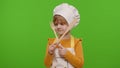 Child girl kid dressed as cook chef with fork and spatula, showing symbol of rejection, disagreement