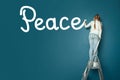 Child girl on ladder writing word Peace on the wall with brush. Social, peace, environment, world concept Royalty Free Stock Photo