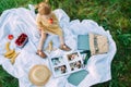 Child girl looks photo album and eats fruits in the park