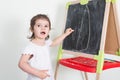 Child girl makes chalk drawings on a chalkboard