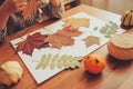 Child girl making herbarium from dried leaves at home, nature art and craft