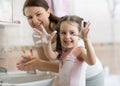Pretty woman and daughter child girl washing hands with soap in bathroom