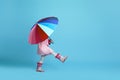 Child girl with multicolored umbrella in pink rain coat