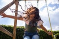 child girl at the playground playing on a swing, hispanic kid smiling and having fun at the park, low angle shot Royalty Free Stock Photo
