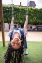 child girl at the playground playing on a swing upside down, hispanic kid smiling and having fun at the park Royalty Free Stock Photo