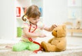 Child girl playing doctor and curing plush toy Royalty Free Stock Photo