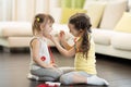 Child girl, playing doctor with her little sister at home in living room Royalty Free Stock Photo