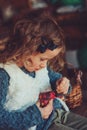 Child girl playing with easter eggs and handmade decorations in cozy country house