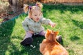 Child girl playing with ginger cat in spring garden Royalty Free Stock Photo