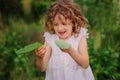 Child girl playing with leaves in summer forest with birch trees. Nature exploration with kids. Royalty Free Stock Photo