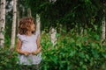 Child girl playing with leaves in summer forest with birch trees. Nature exploration with kids.