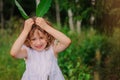 Child girl playing with leaves in summer forest with birch trees. Nature exploration with kids. Royalty Free Stock Photo