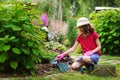 child girl playing little gardener and helping in summer garden, Royalty Free Stock Photo