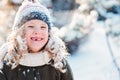 Child girl playing with snow in winter garden or forest, making snowballs and blowing snowflakes Royalty Free Stock Photo