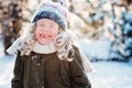 Child girl playing with snow in winter garden or forest, making snowballs and blowing snowflakes