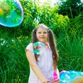 Child girl playing with soap bubble wand in the park Royalty Free Stock Photo