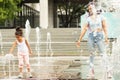 Child girl playing with water in the fountain with mom, family relationships, summer, walk in the park Royalty Free Stock Photo