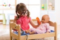 Child girl plays doctor examining baby doll patient with toy otoscope Royalty Free Stock Photo