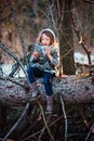 Child girl plays with pine cones on tree log in winter forest Royalty Free Stock Photo