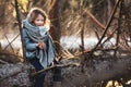 Child girl plays with pine cones on tree log in winter forest Royalty Free Stock Photo