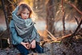 Child girl plays with pine cones on tree log in winter forest Royalty Free Stock Photo