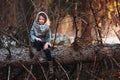 Child girl plays with pine cones on tree log in winter forest Royalty Free Stock Photo