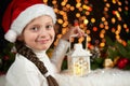 Child girl portrait with christmas decoration, dark background with lights, face expression and happy emotions, dressed in santa h Royalty Free Stock Photo