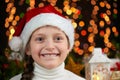 Child girl portrait in santa hat with christmas decoration, dark background with lights, face expression and happy emotions, winte Royalty Free Stock Photo