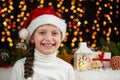 Child girl portrait in santa hat with christmas decoration, dark background with lights, face expression and happy emotions, winte Royalty Free Stock Photo