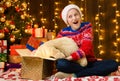 Child girl posing in new year or christmas decoration, wearing a red sweater and a Santa hat, she opening a gift box and having Royalty Free Stock Photo