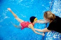 Child girl is practicing swimming in pink bathing suit in pool, coach will conduct training swim Royalty Free Stock Photo