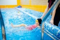 Child girl is practicing swimming in pink bathing suit in pool, coach will conduct training swim Royalty Free Stock Photo