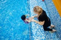 Child girl is practicing swimming in pink bathing suit in pool, coach will conduct training swim Royalty Free Stock Photo