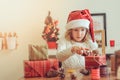 Child girl preparing gifts for christmas at home, cozy holiday interior