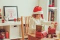 Child girl preparing gifts for christmas at home, cozy holiday interior