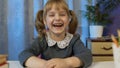 Child girl pupil studying homework during online lessons at home, kid laughing, looking at camera Royalty Free Stock Photo