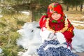 Child girl in Russian pavloposadskie folk scarf on head with floral print and with bunch of bagels on background of snow. Royalty Free Stock Photo