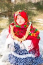 Child girl in Russian pavloposadskie folk scarf on head with floral print and with bunch of bagels on background of snow. Royalty Free Stock Photo