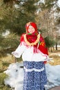 Child girl in Russian pavloposadskie folk scarf on head with floral print and with bunch of bagels on background of snow. Royalty Free Stock Photo