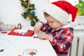 Child girl in Santa hat making christmas card from paper Royalty Free Stock Photo