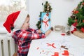 Child girl in Santa hat making christmas greeting card with snowman Royalty Free Stock Photo