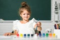 Child girl at school draws with paints. Kids artist creativity. Funny school girl face. Royalty Free Stock Photo